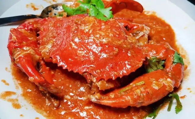 Singapore chilli crab served in spicy tomato egg gravy with deep-fried mantou buns at a seafood restaurant